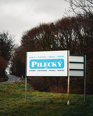 Venkovní billboard Pilecký u silnice s textem výroba, distribuce, montáž