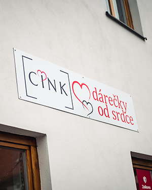 Reklamní cedule na fasádě obchodu s nápisem Dárečky od srdce